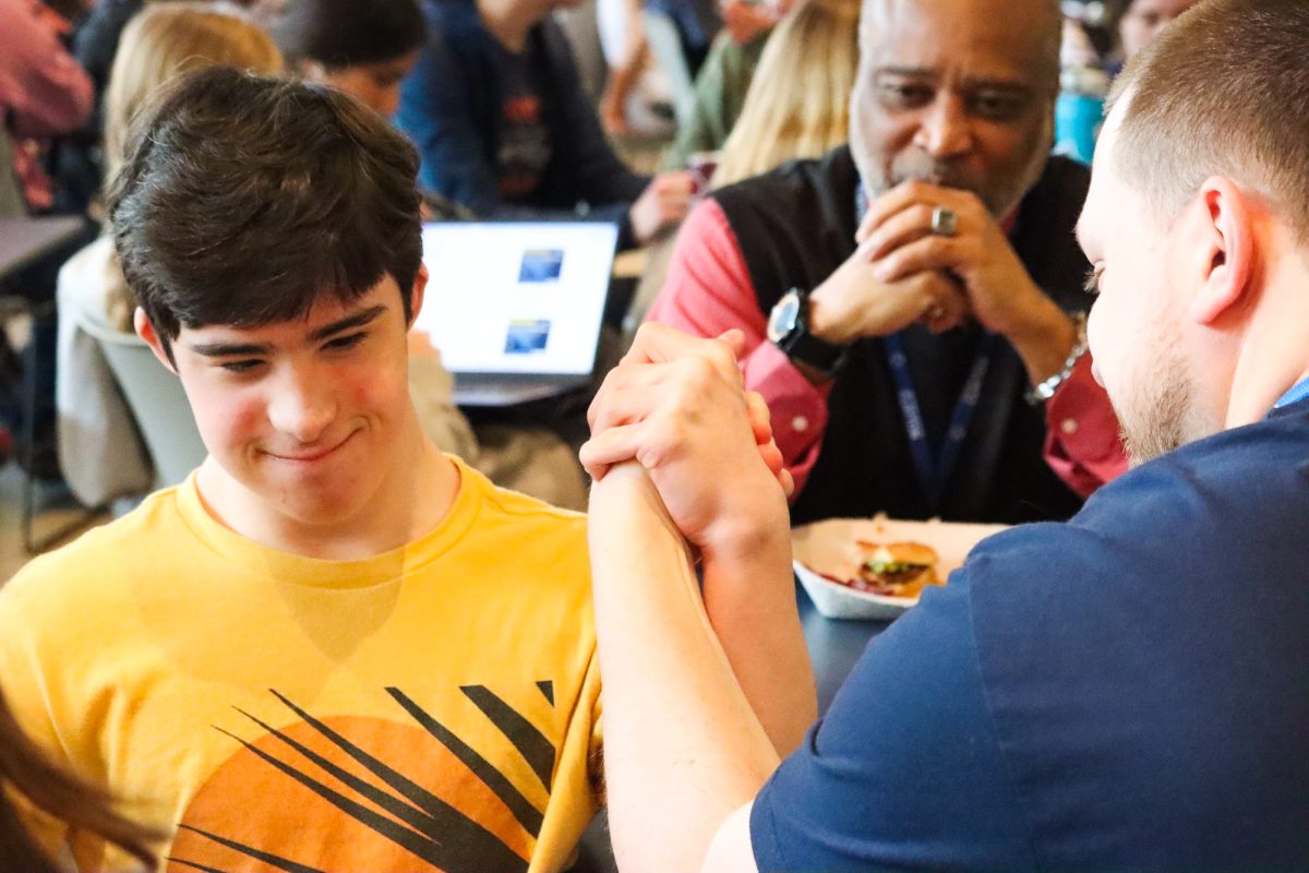 Junior Owen Hayden arm wrestles a paraprofessional in the Commons. During a Best Buddies meeting for Spread the Word Inclusion Day, nearly all club members participated in an impromptu arm wrestling tournament.
