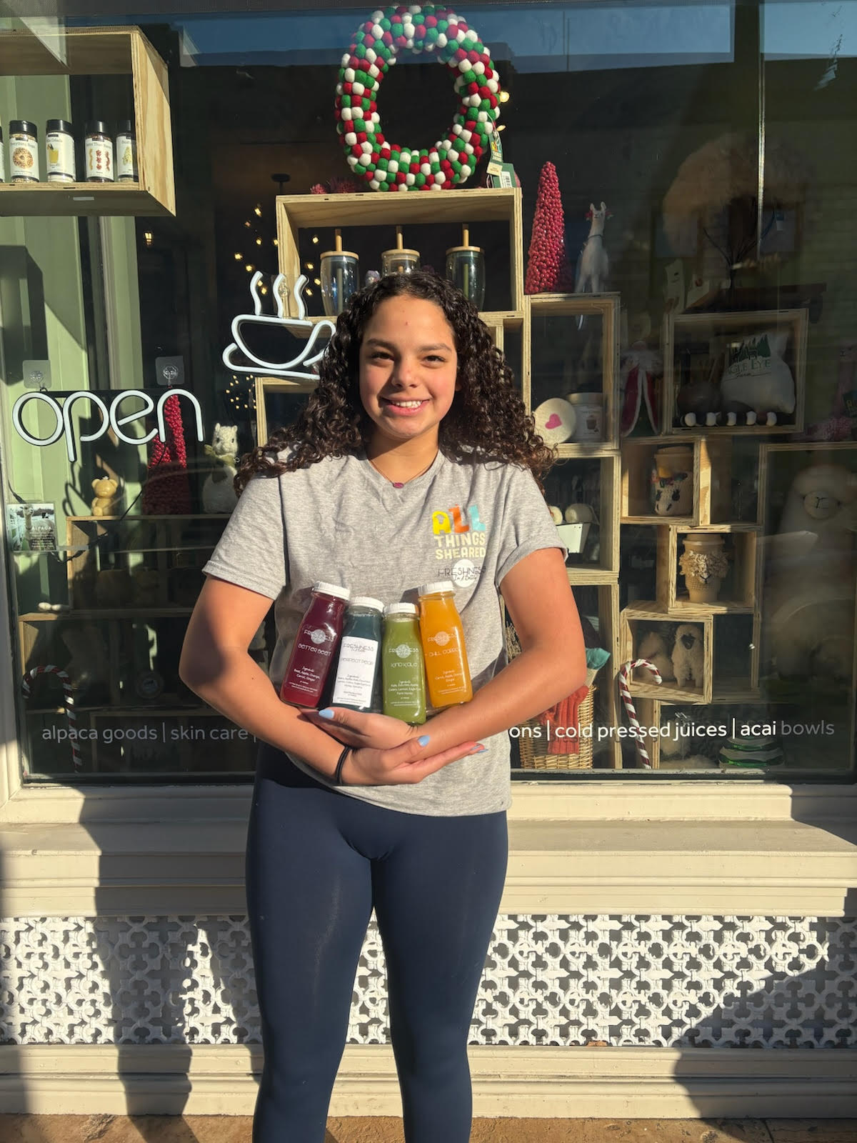 Freshman Berklie Dias stands in front of her juice shop Freshness in a Bottle.