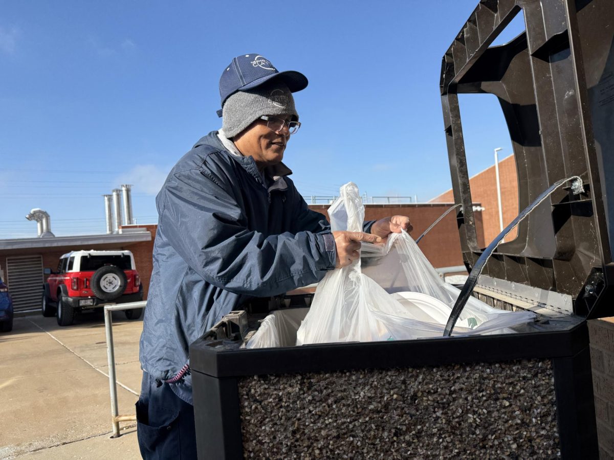 Munirol (Runo) Islam lowers a bag into the dumpster outside the CTE hallway on a 43°F monring, Dec. 3. ADD QUOTE
