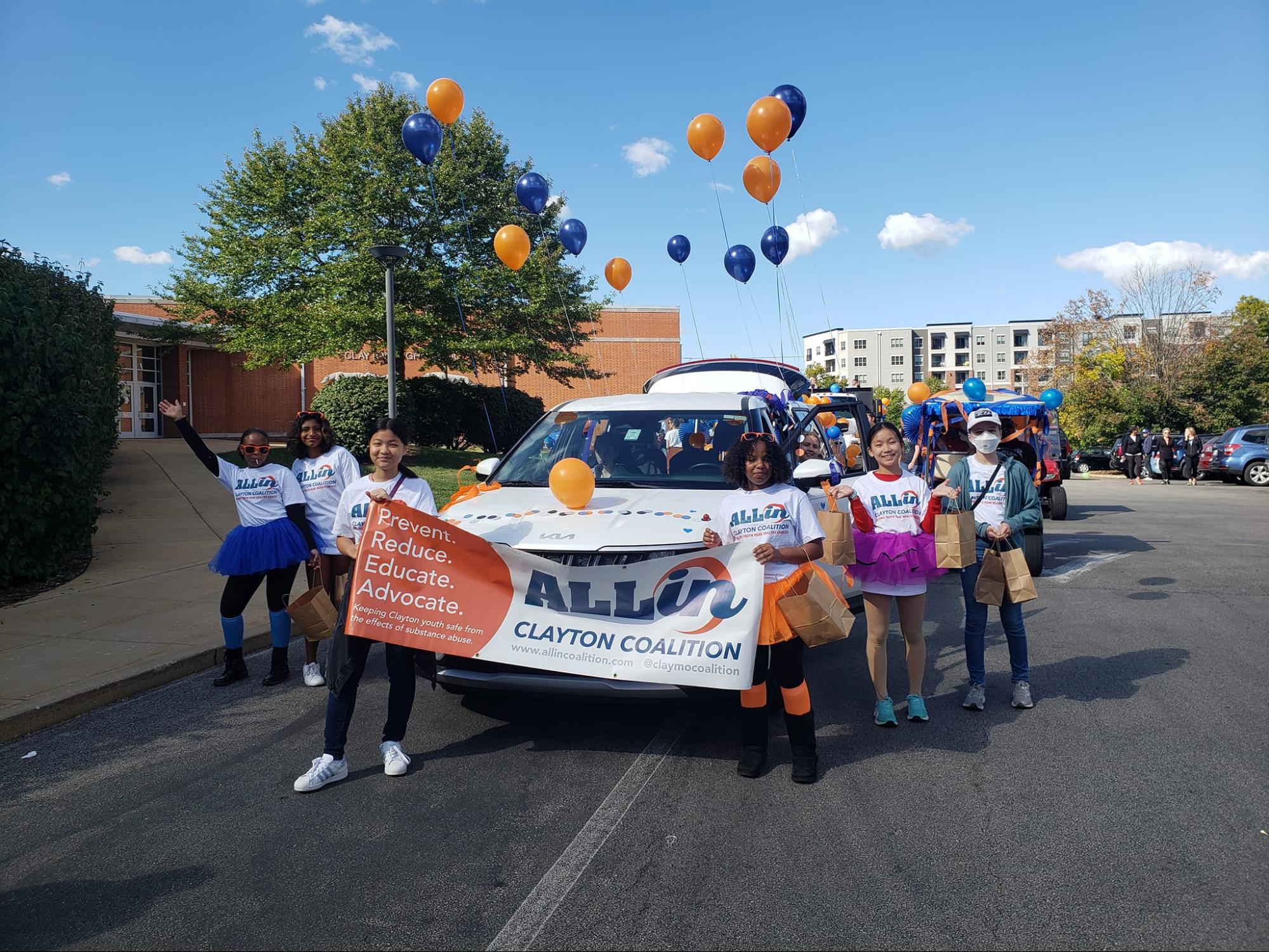 The All-In Coalition marches in the 2022 Homecoming Parade. The students spent the morning decorating the car and threw out frisbees and candy in the parade. ¨[I wanted to] go to the parade [to] get to know everyone better and find common interests besides wanting to combat teen substance abuse,¨ freshman Olivia Lin (pictured left holding the banner) said. 