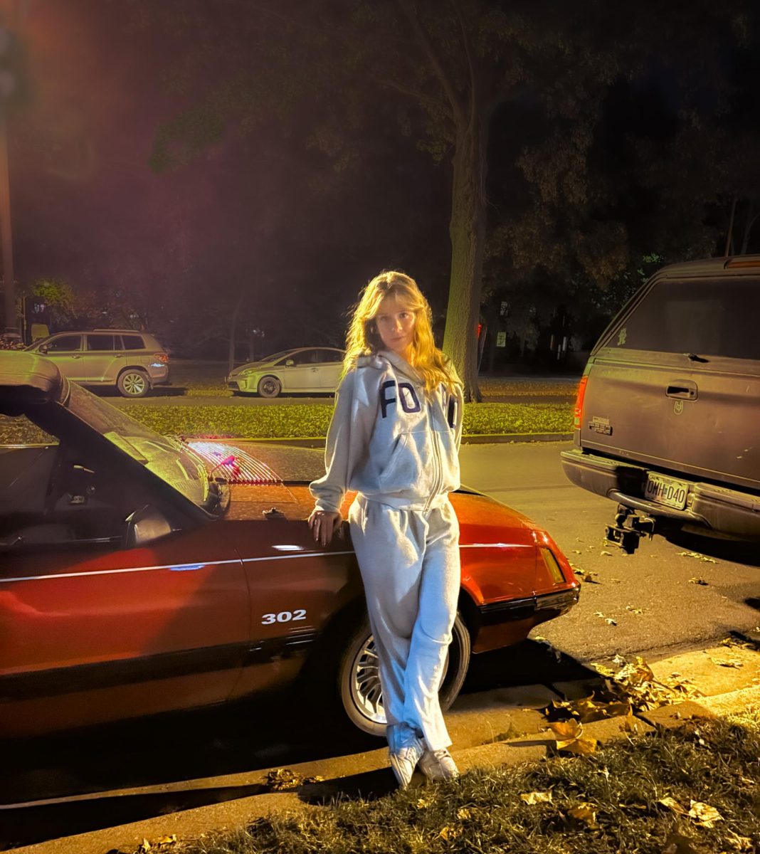 Junior Ema McGee leans against the side of her bright red Foxbody Mustang. She bought it a month after moving to Clayton from Facebook Marketplace with money saved while working at a coffee shop in Ashland. “I’ve always loved Mustangs, especially Fox Body Mustangs. I just love the way that they look and the way they drive. I’ve had an obsession with them. And I knew when I was getting my first car, that I wanted to have one that was older,” McGee said. 
