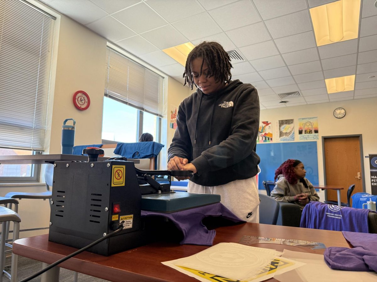 Senior Lauren Young, a member of Hounds House--a student-run business created through the Catalyst program--carefully presses t-shirts for the event.